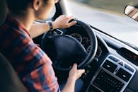 Close-up view of a man driving a modern car, showing dashboard and steering details.